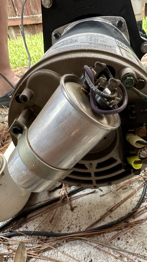 Close-up photo of the failed capacitor at the rear of the filter pump just before removal.
