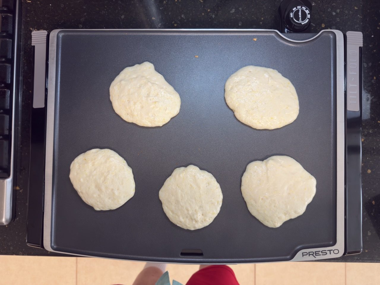 five 6-inch pancakes cooking on a Presto Tilt & Fold Griddle.